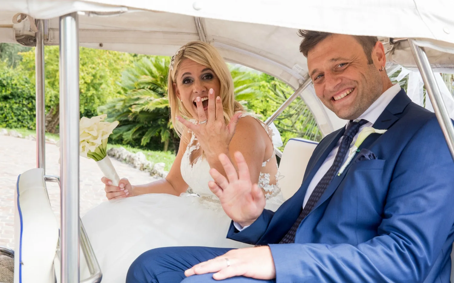 Les mariés souriants montrent leurs alliances dans la voiture