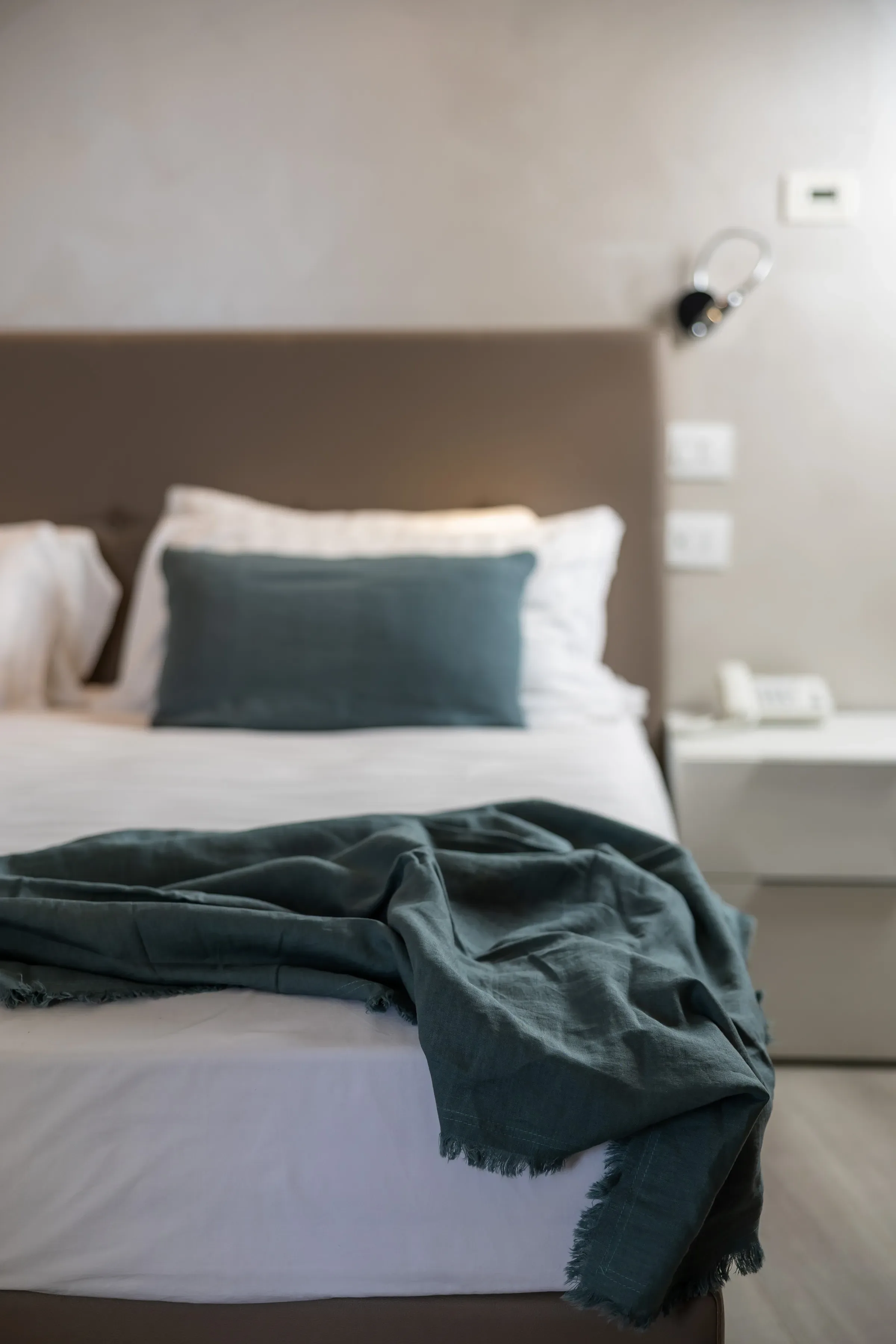 Nowoczesne łóżko z zielonym kocem i białymi poduszkami