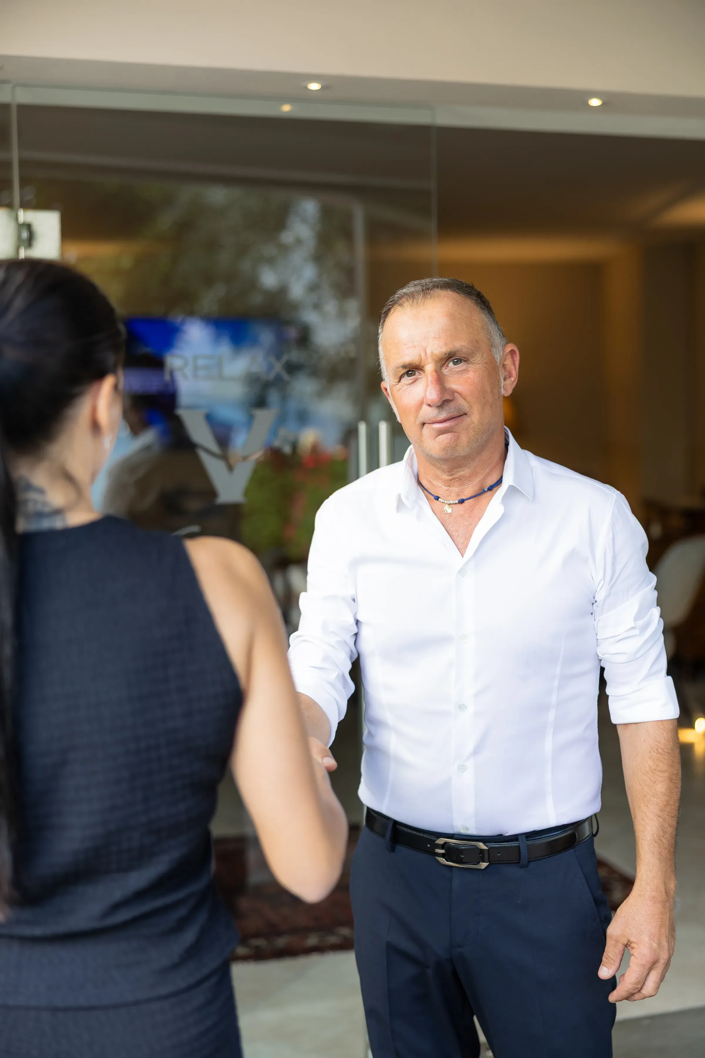 Mężczyzna wita gościa przed wejściem do hotelu