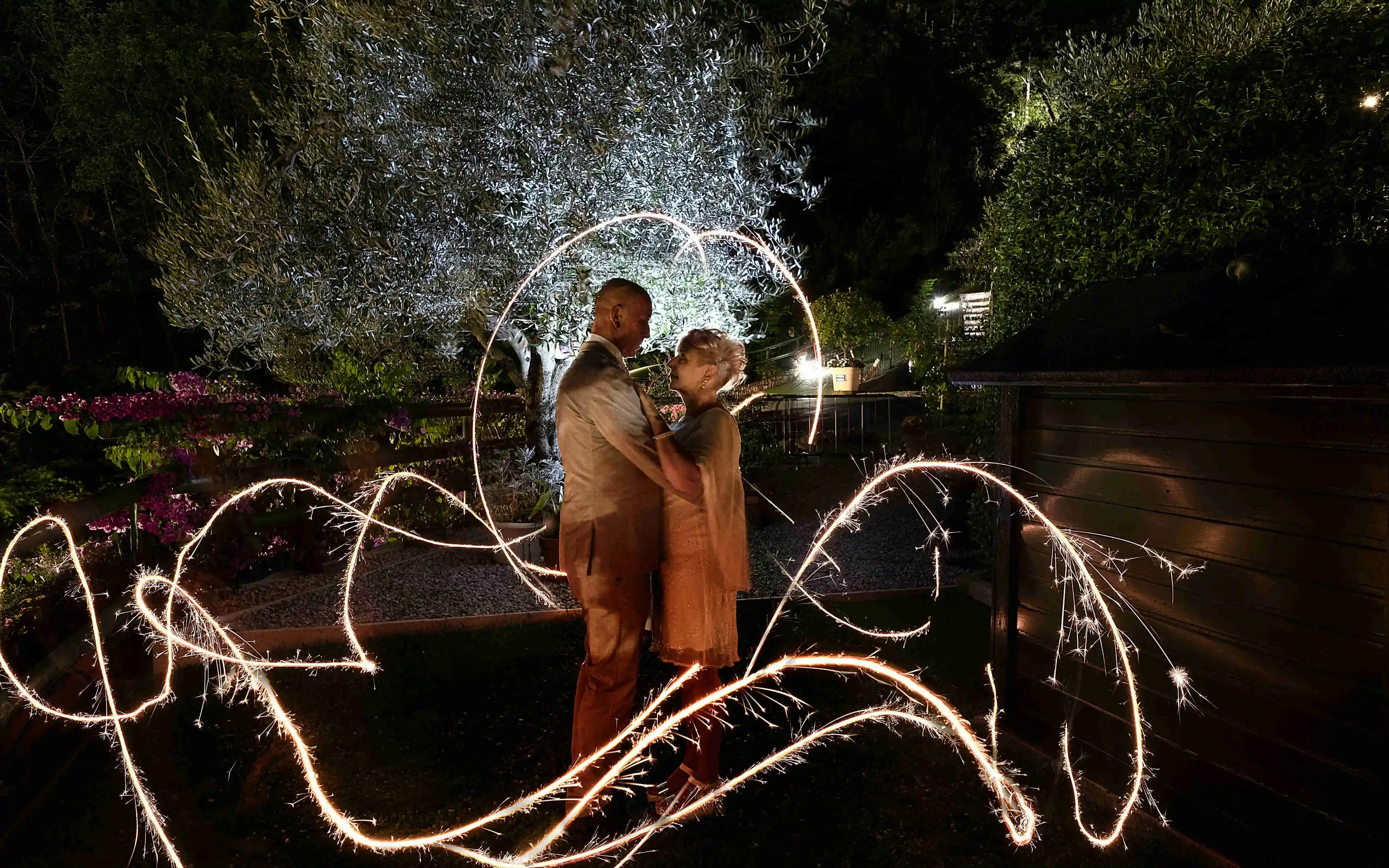 Romantic couple embracing with sparklers in a garden at night