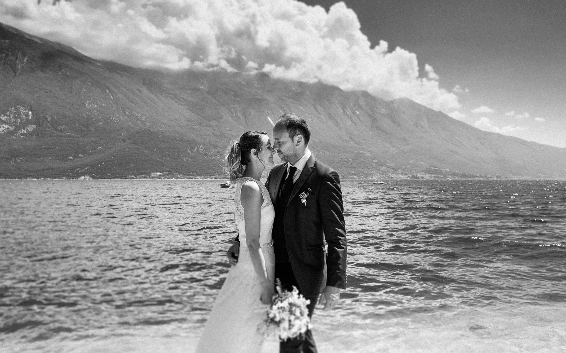 Wedding couple embracing on beach with mountain backdrop